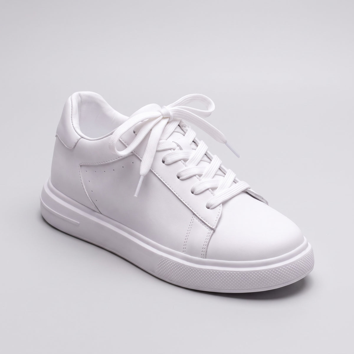 The Apex white leather sneaker, three-quarter view on a soft grey studio background