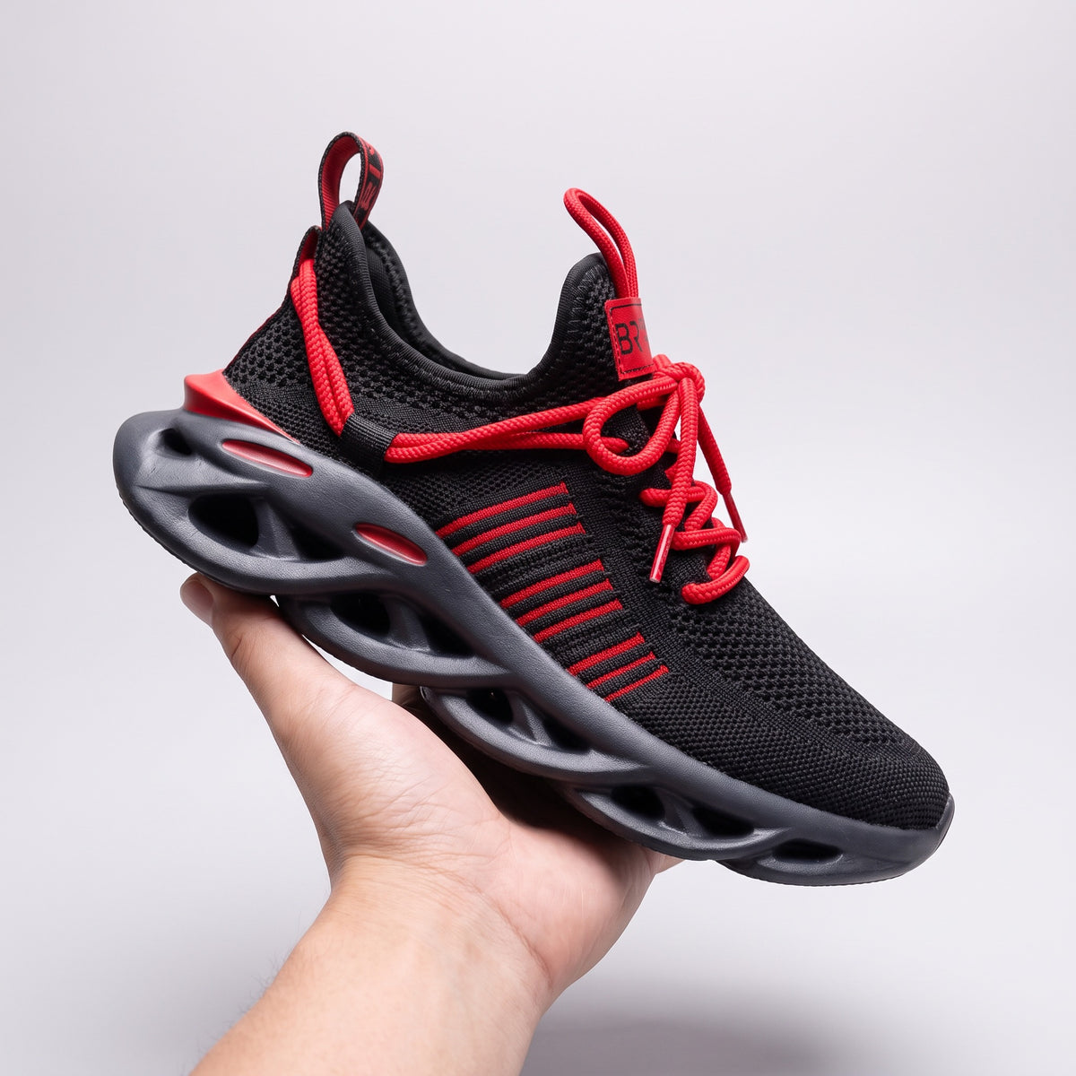 Bold Ranger sneaker in black and red, held in one hand