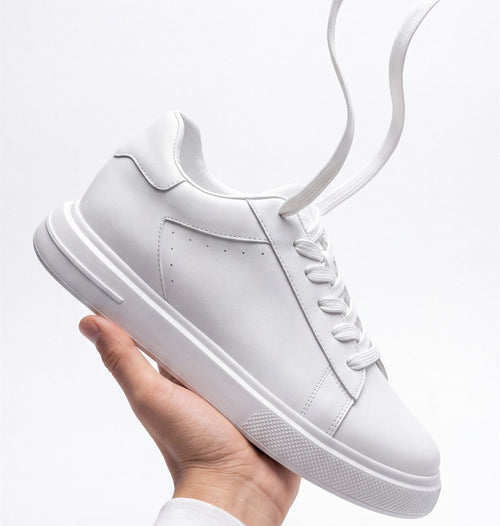 The Apex white leather sneaker, held up in an open hand against a pale grey background
