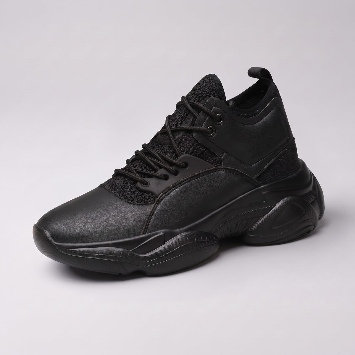The Ridge chunky trainer in black, three-quarter view on a pale grey studio background