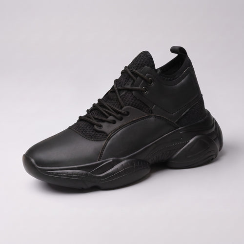 The Ridge chunky trainer in black, three-quarter view on a pale grey studio background