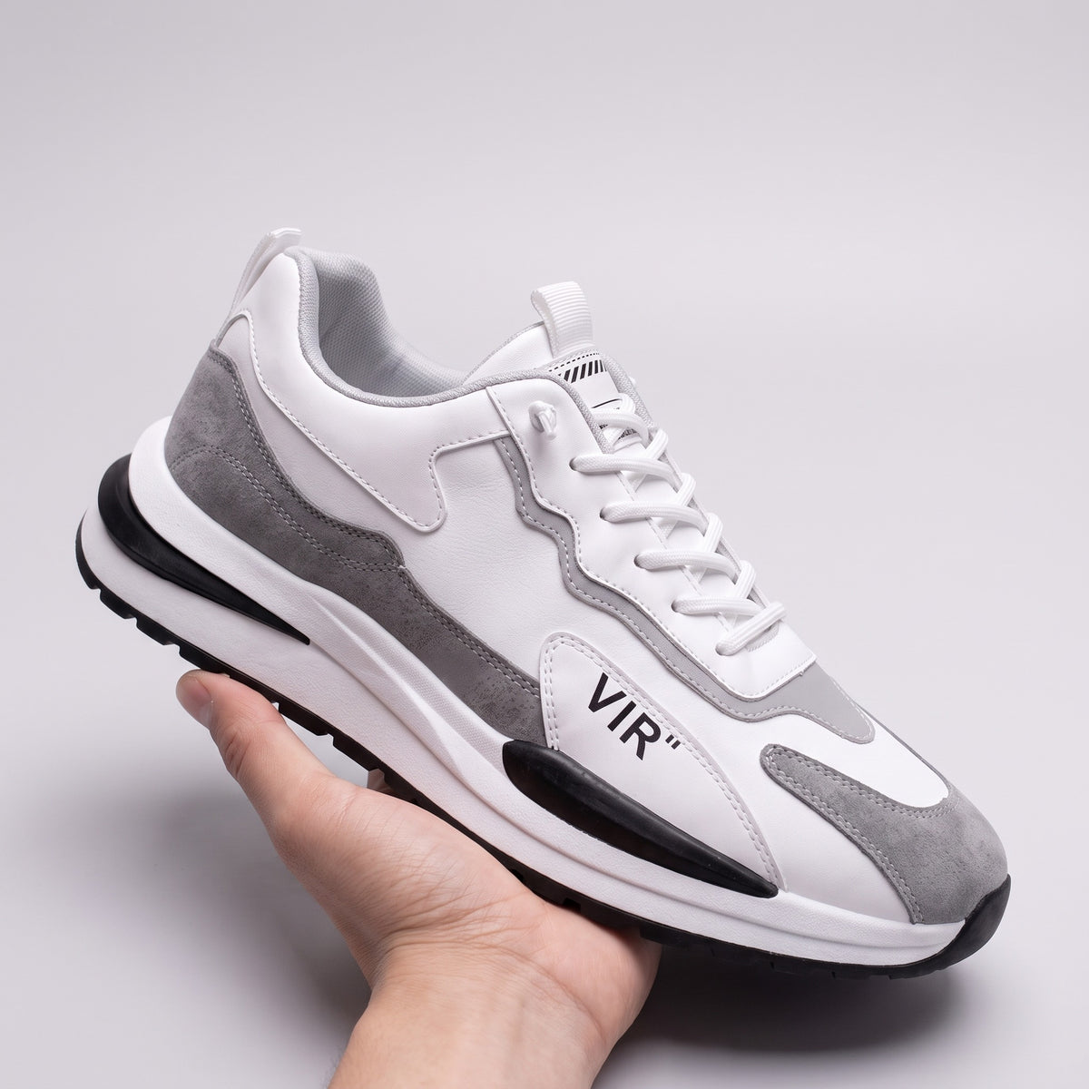 Vintage in Rwanda sneaker in white and grey, held in one hand